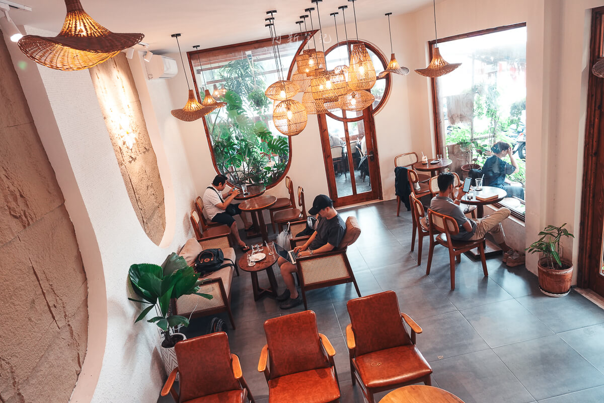 Cafeholic Coffee 室內用餐區，呈現桌椅配置、吊燈與綠色植栽