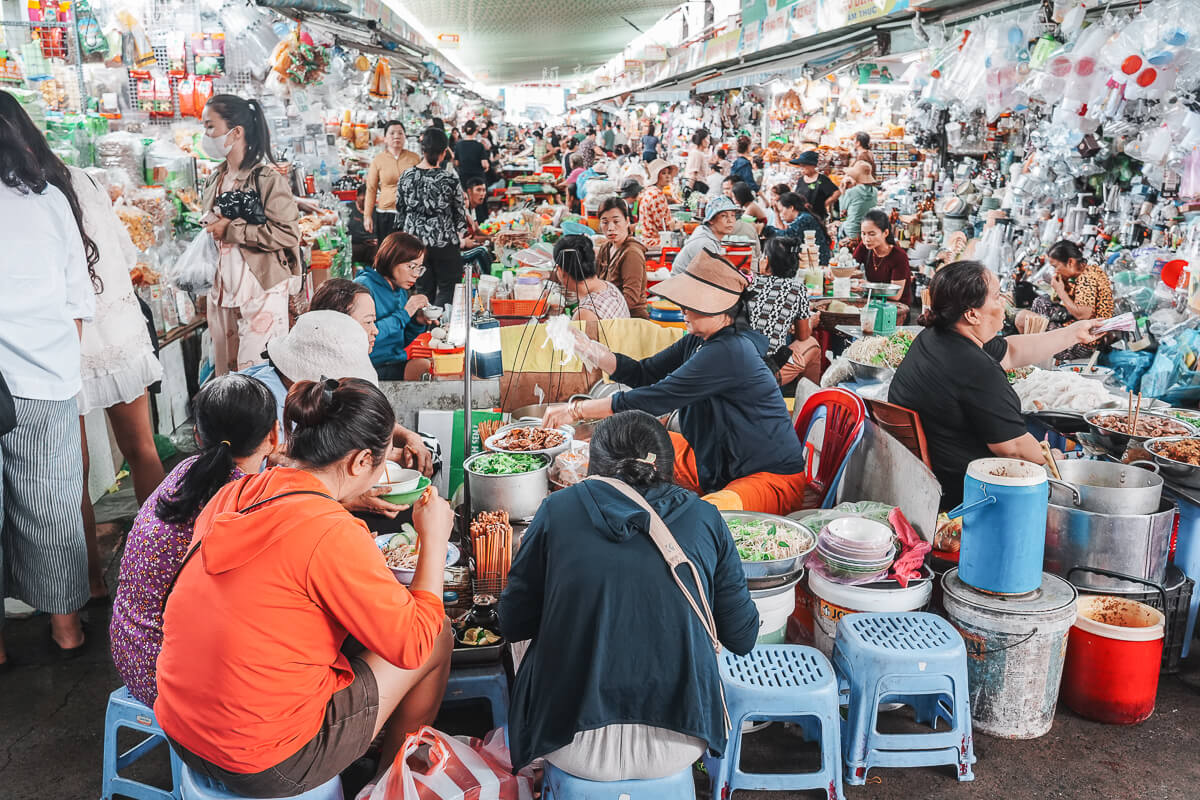 峴港共市場外圍棚子下，大批客人蹲在地上翻找堆放的二手衣服