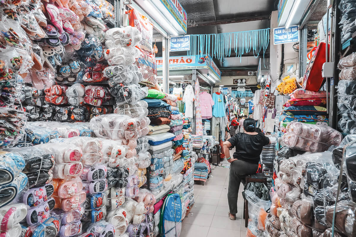 峴港共市場雜貨區走道，兩側陳列密集商品