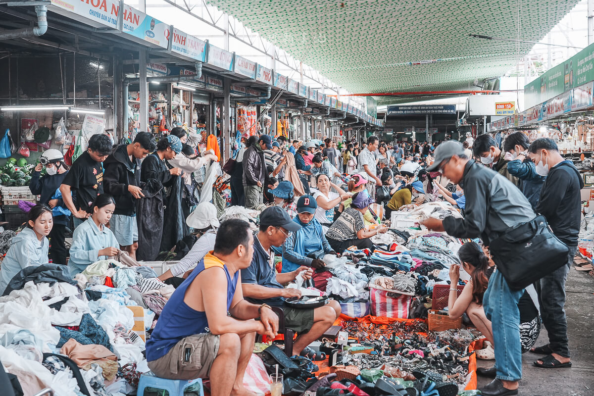 峴港共市場小吃區坐滿用餐客人，攤位沿走道排列，牆上掛滿招牌