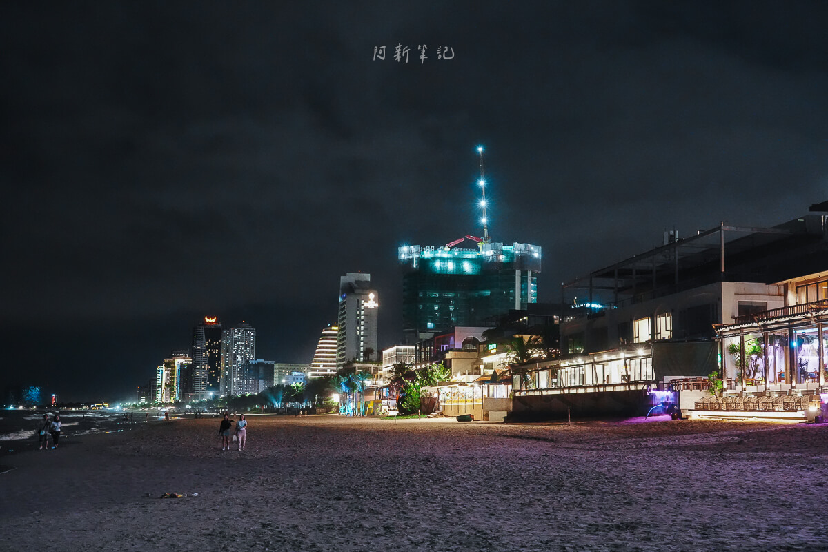 峴港美溪沙灘夜晚的燈光、遠方高樓與沙灘上散步的人