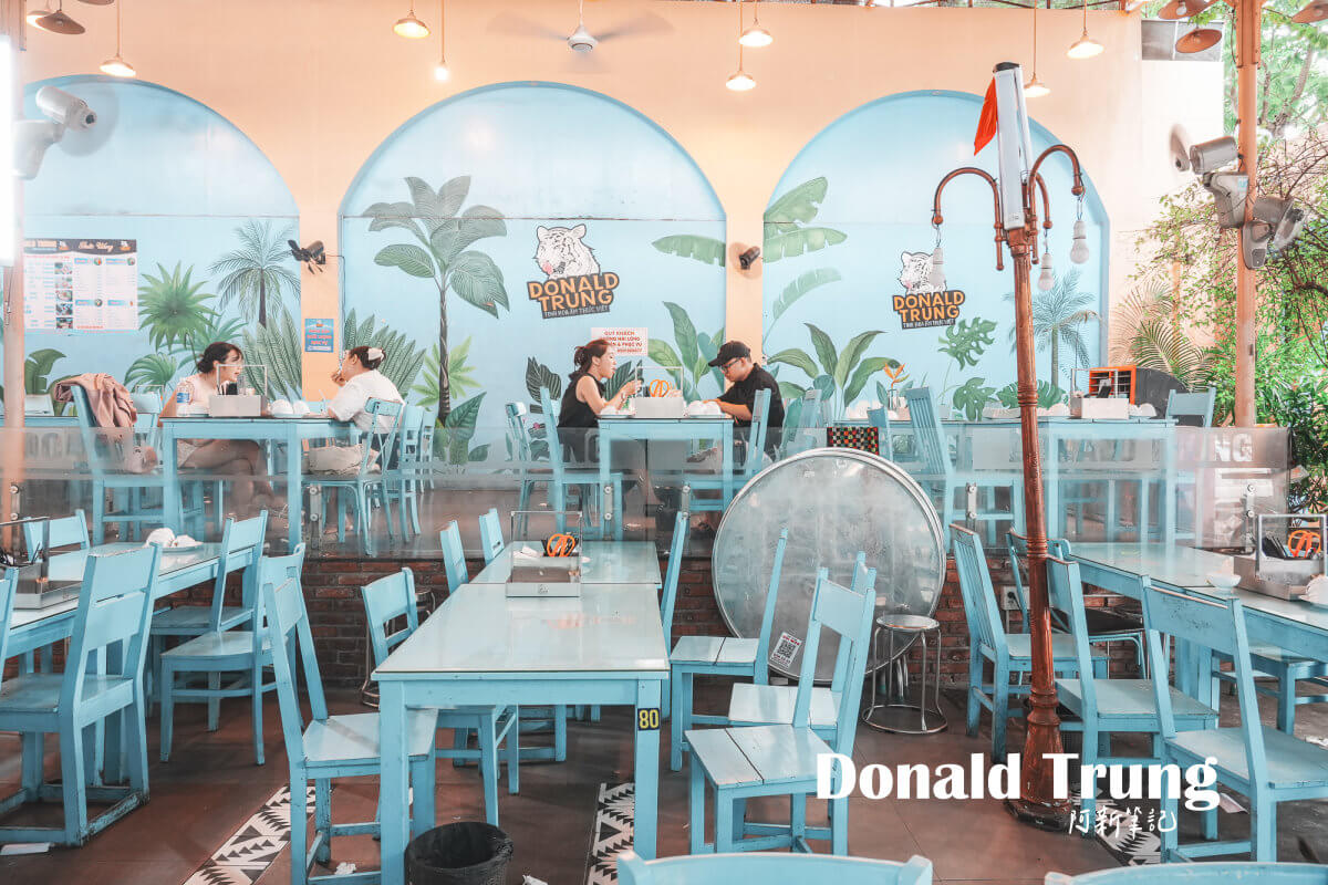 峴港 Donald Trung,峴港必吃,峴港米紙豬肉捲 峴港 Donald Trung 店內的淺藍色桌椅、拱形鏡面與熱帶植物壁畫