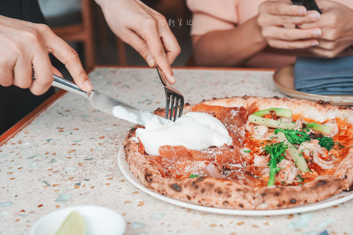 用餐者在峴港 Pizza 4P's Indochina 餐桌上用刀叉切開披薩中央的布拉塔起司