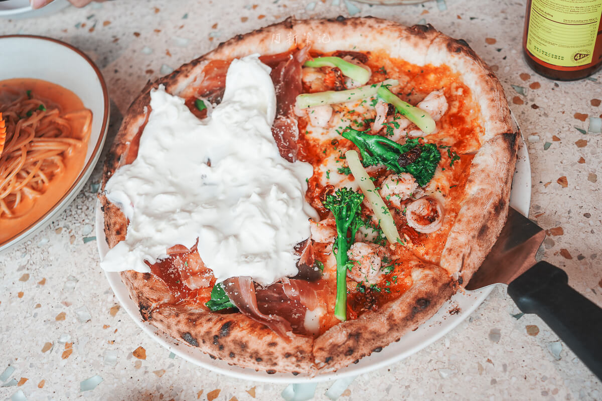 峴港 Pizza 4P's Indochina 柴燒披薩邊緣焦斑，中間鋪著布拉塔起司、火腿、蝦仁與青花筍