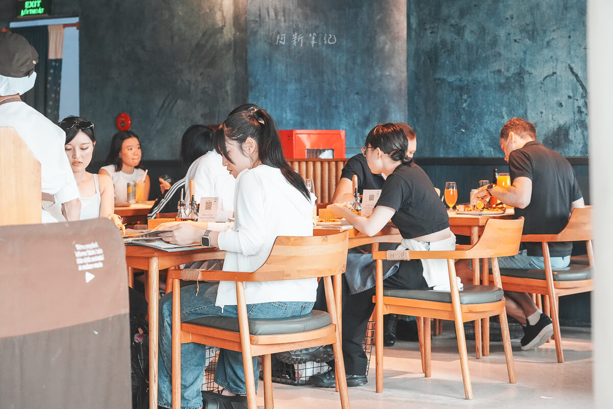 峴港 Pizza 4P's Indochina 用餐區的客人、藍灰色牆面與木桌上的調味料盒