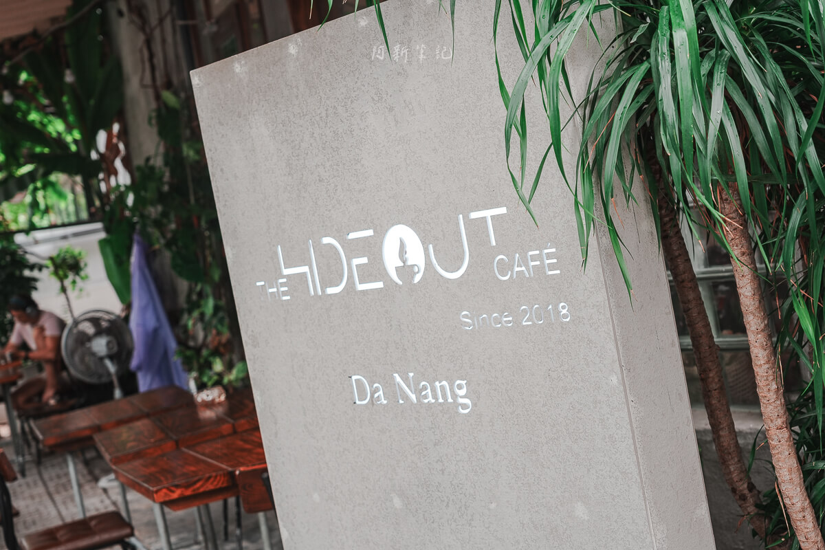 峴港 The Hideout Cafe 招牌,峴港咖啡 峴港 The Hideout Cafe 灰色水泥招牌,鏤空刻字 Since 2018 Da Nang,旁邊是綠色植物