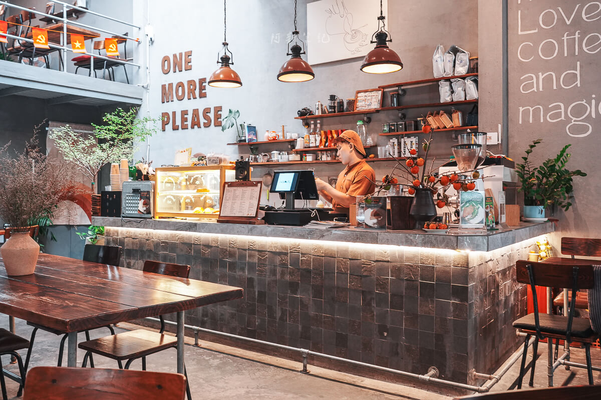 峴港 The Hideout Cafe 店內吧檯、咖啡豆層架與 ONE MORE PLEASE 字樣