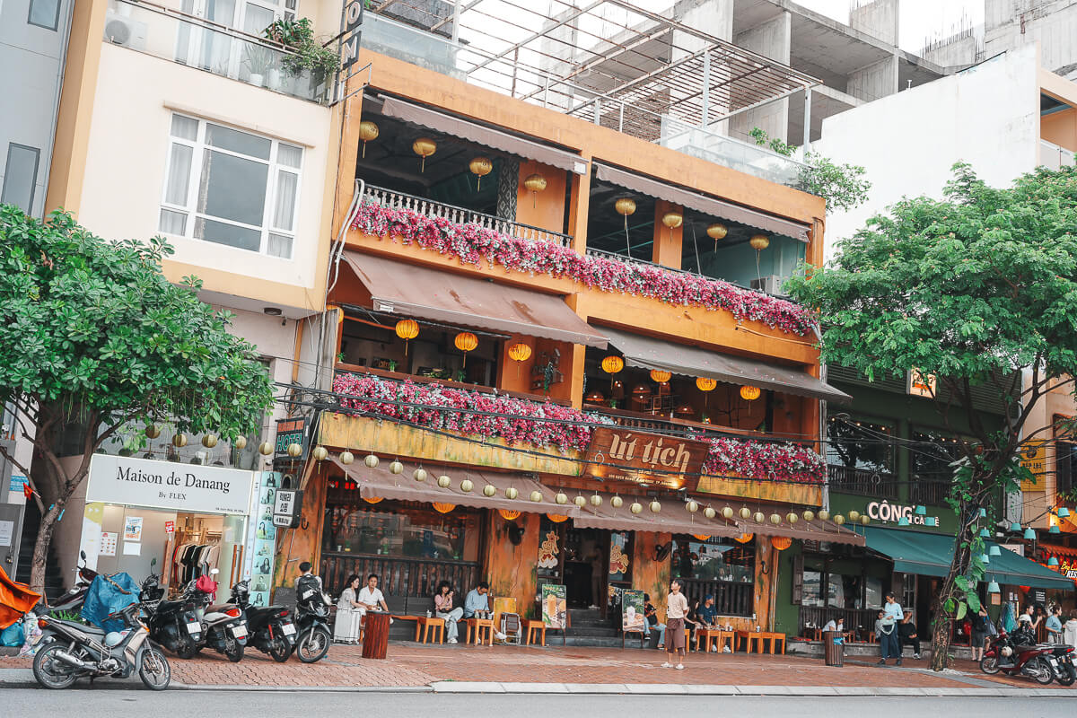 峴港 Ut Tich Cafe 橘黃色三層樓外觀，陽台掛滿燈籠與九重葛