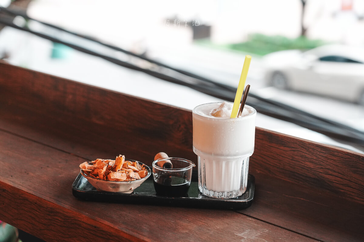 峴港 Ut Tich Cafe 窗邊木桌上的椰子咖啡、小壺濃縮與椰子脆片